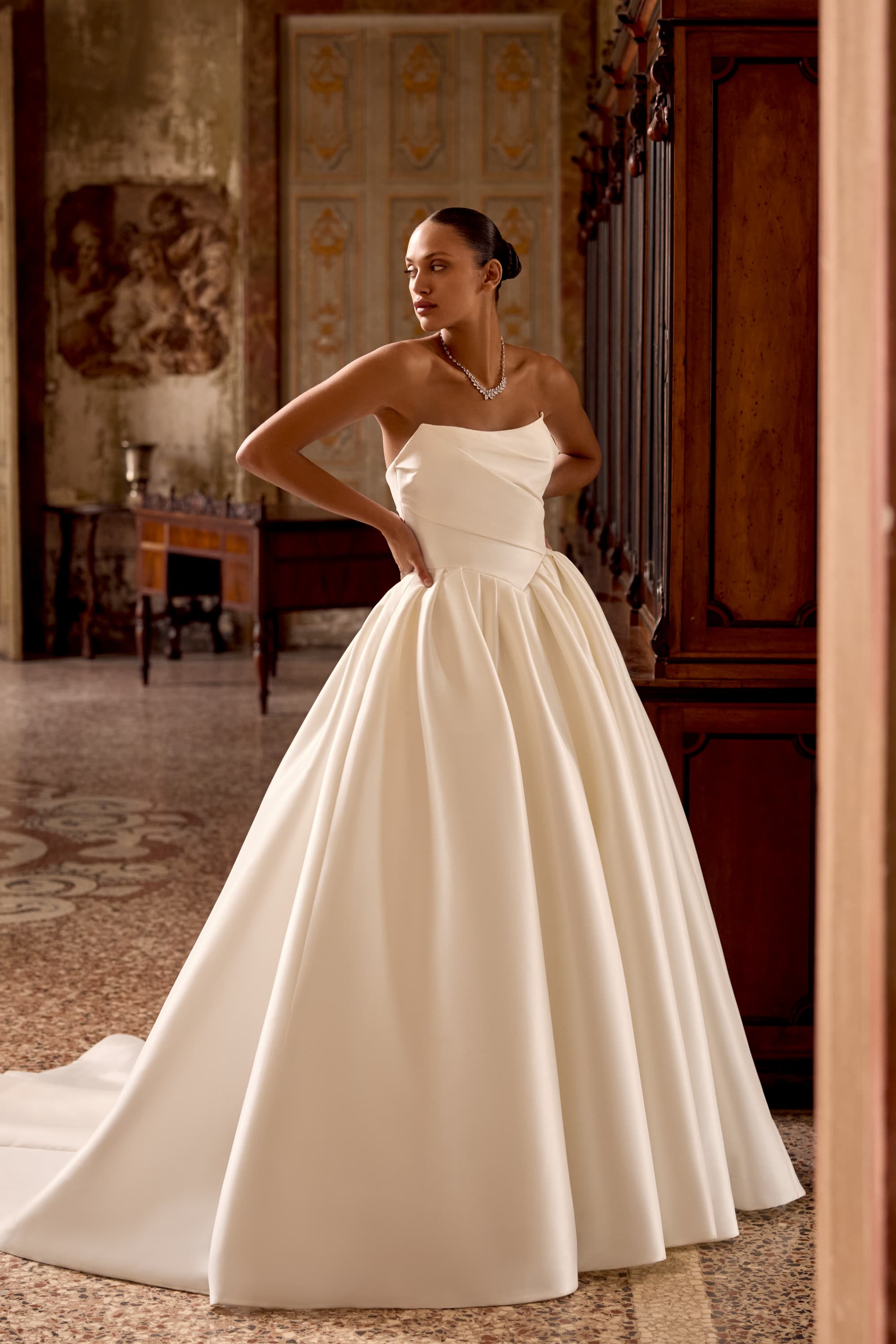 Bride in a sculptural satin wedding gown in an ornate interior